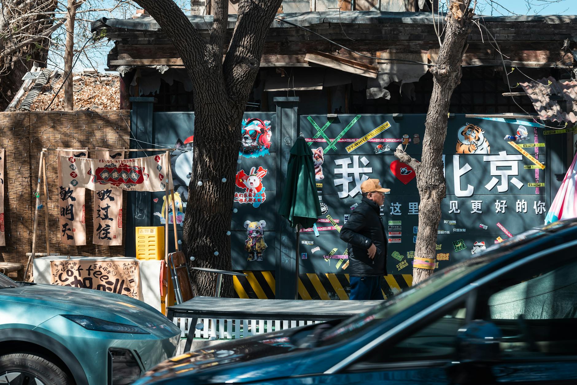 Urban street view in Beijing showcasing a man walking, colorful graffiti, and parked cars.
