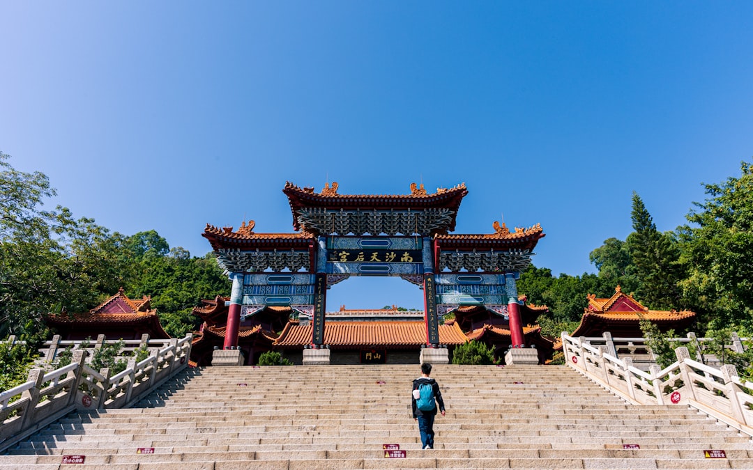 Person walks up stairs towards traditional chinese gate.
