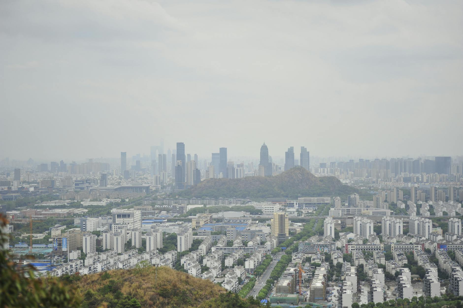 A panoramic view of a sprawling urban cityscape with skyscrapers and a misty atmosphere.