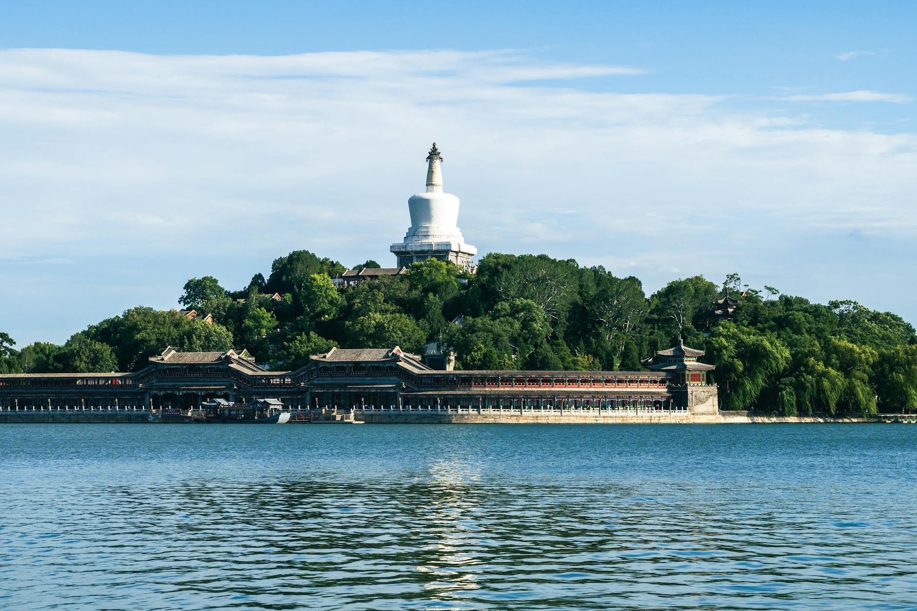 Scenic view of the iconic White Pagoda in Beihai Park, Beijing, with surrounding greenery and water.
