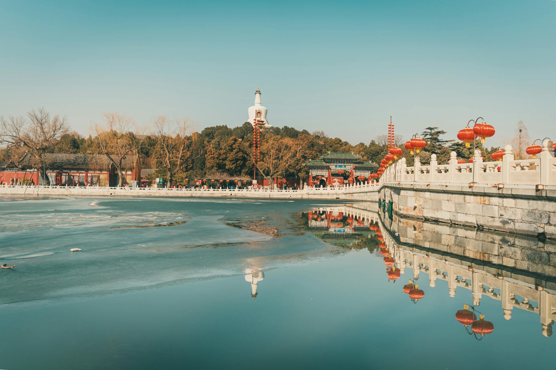 Tranquil scene of Beihai Park in Beijing with reflections of the White Pagoda and festive lanterns.