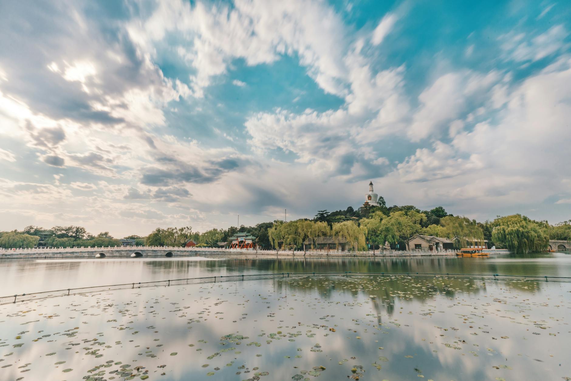 Beautiful view of Beihai Park's lake and white pagoda reflecting in calm waters in Beijing, China.