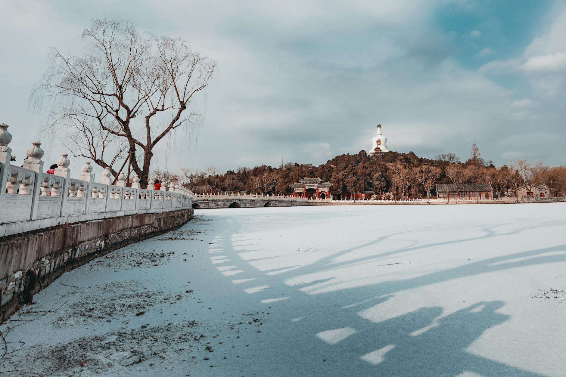 Captured in Beijing's Beihai Park, this scene showcases a frozen lake under a cloudy sky, highlighting the winter beauty.