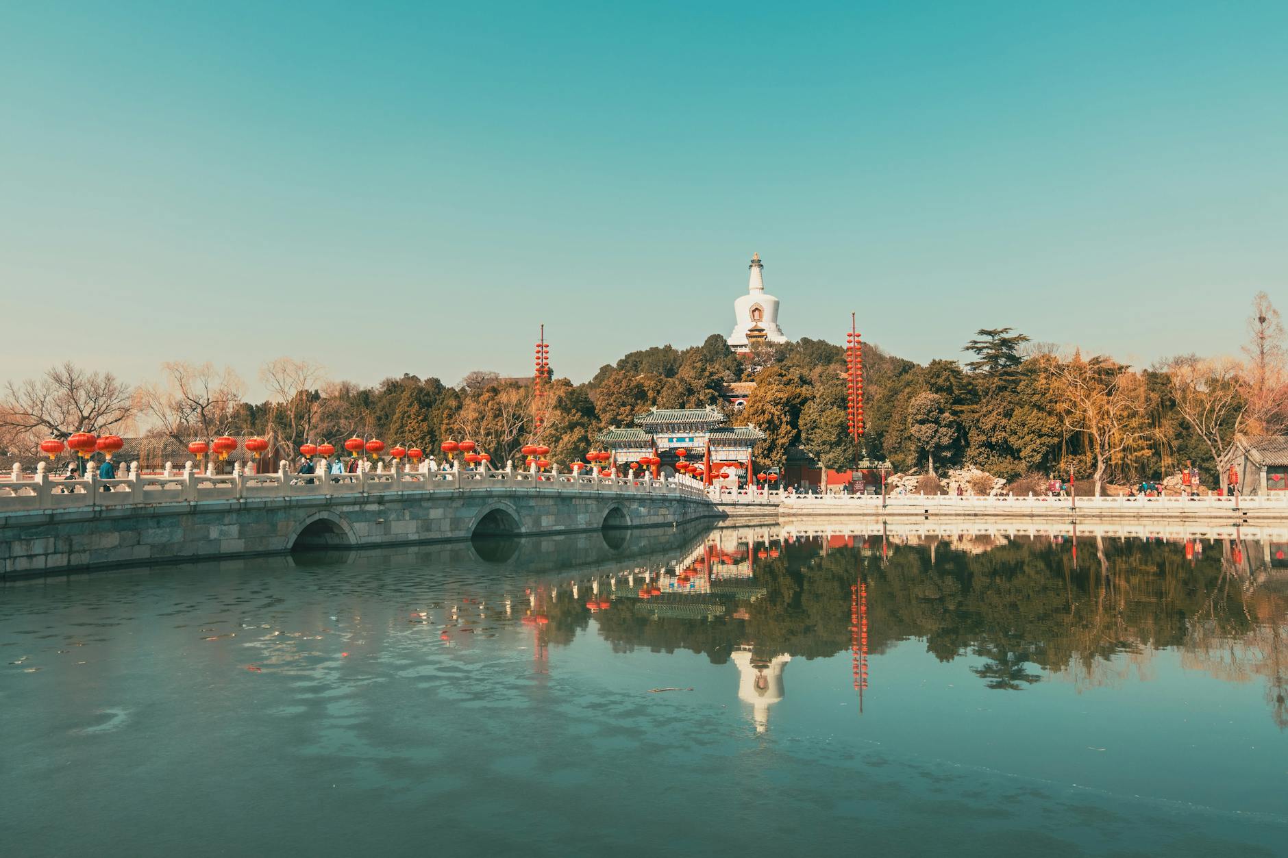 Tranquil reflection of traditional architecture and bridge in Beihai Park, Beijing.