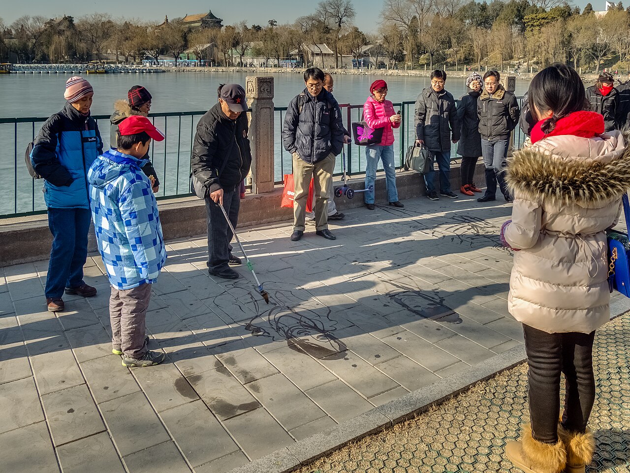 Street painter who creates portraits with water on the frozen ground in Beihai Park in Beijing