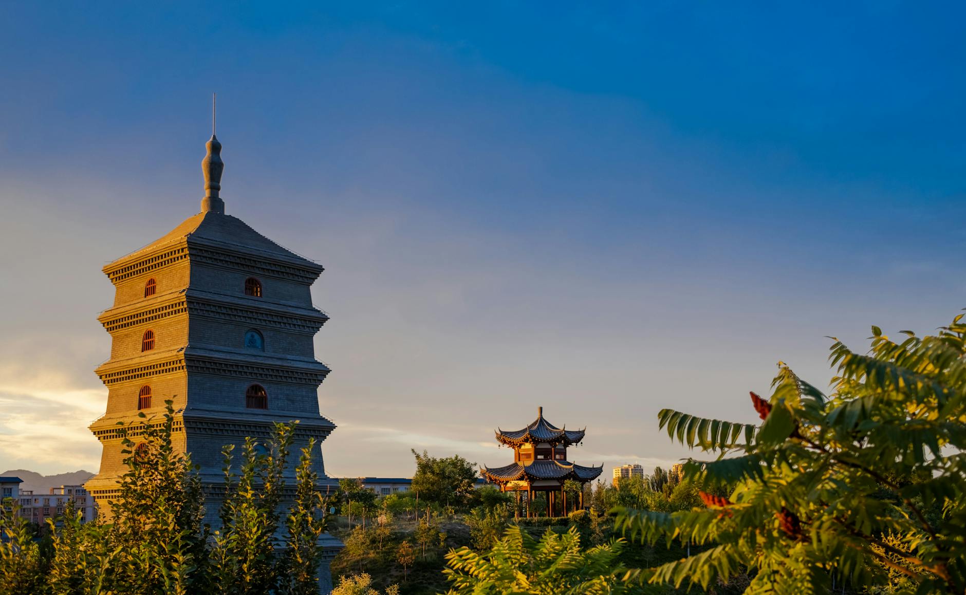 Serene view of the Giant Wild Goose Pagoda in Xi'an with lush greenery and a clear evening sky.