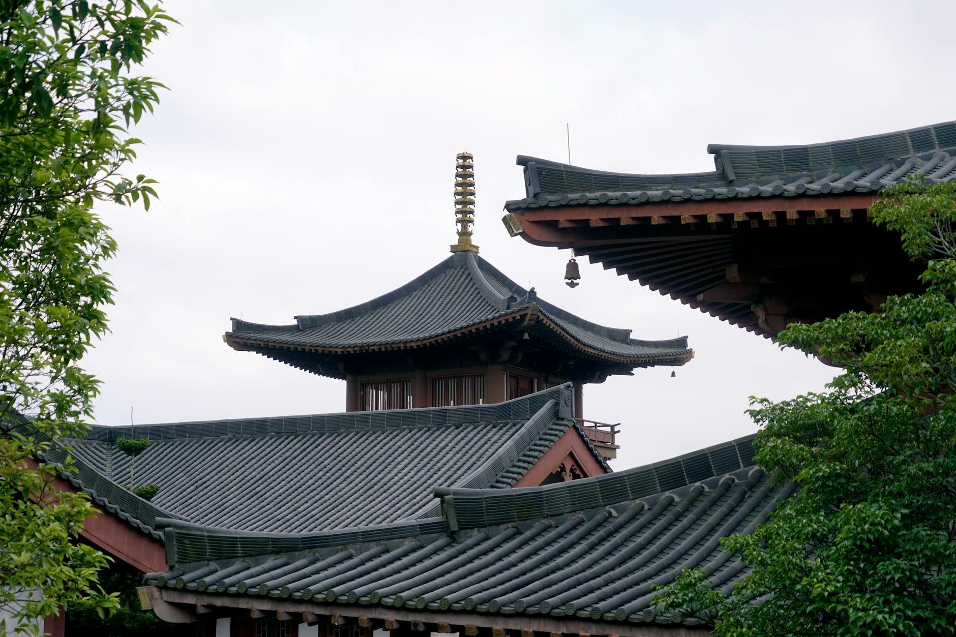 Traditional Buddhist pagoda with ornate tiled roofs surrounded by lush greenery, showcasing tranquility and cultural heritage.