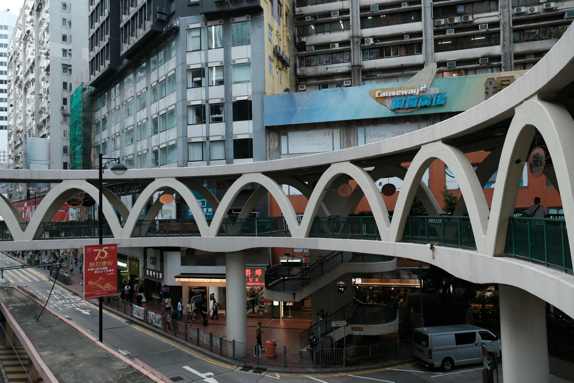 A busy urban street with an elevated walkway in a vibrant city area.