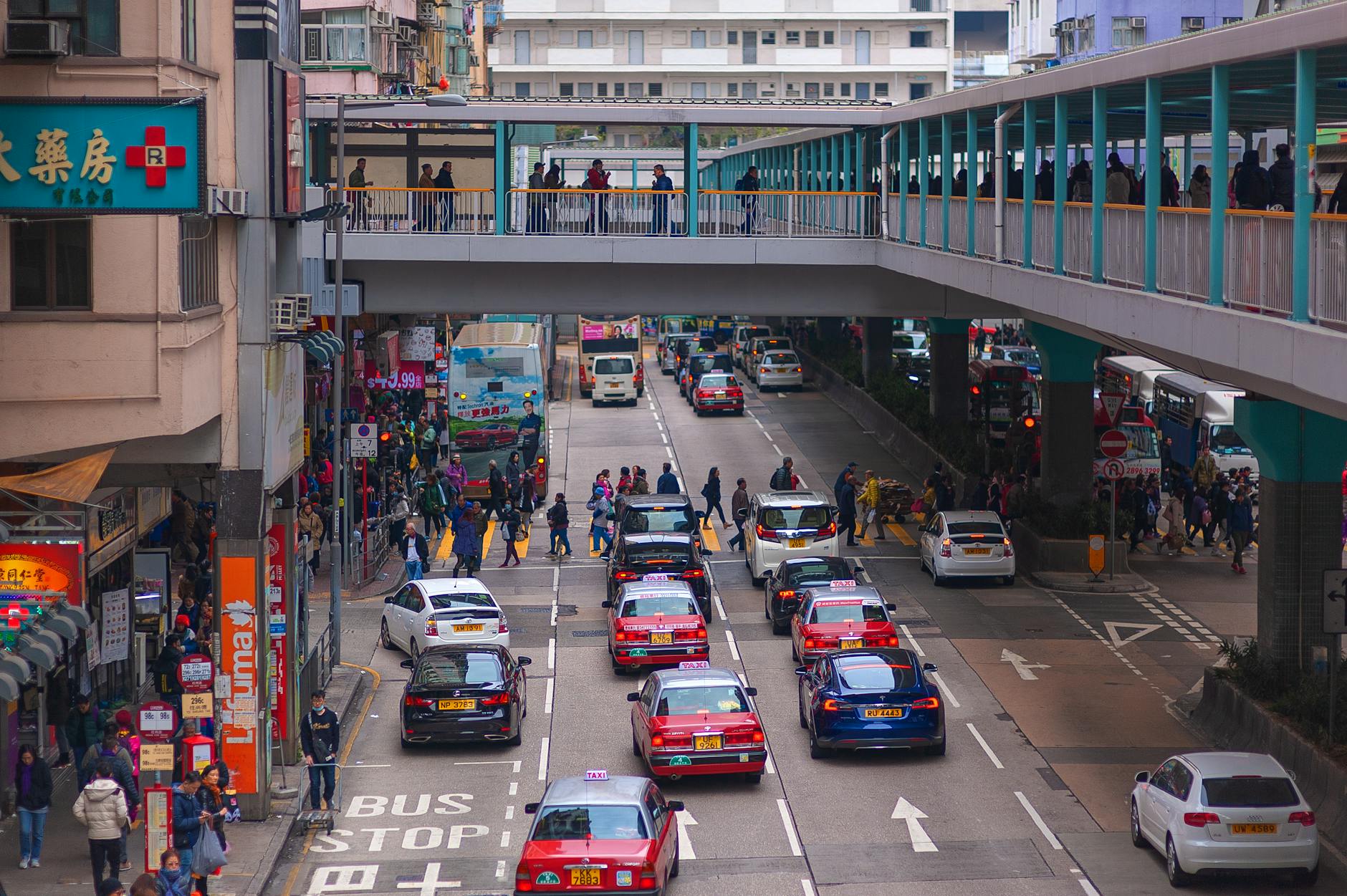 Vibrant city life in Hong Kong with taxis and pedestrians on a bustling street.