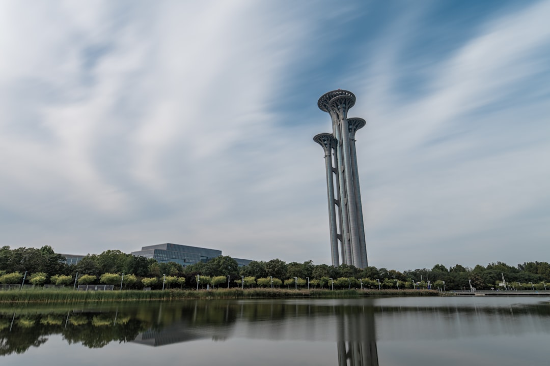 Three tall towers reflected in calm water under sky