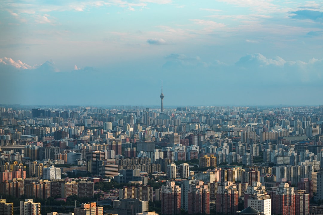 Sprawling cityscape with a distant tower under cloudy sky.