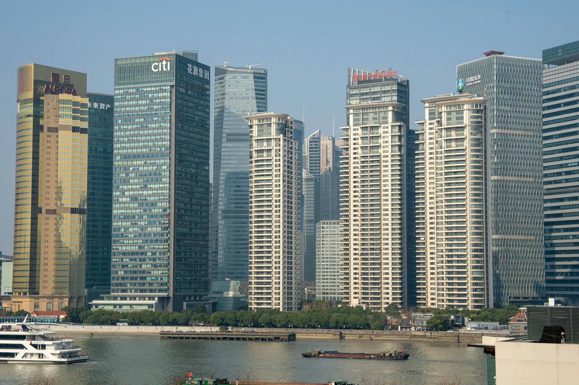 Sunlit view of Pudong's modern skyscrapers across the Huangpu River in Shanghai.