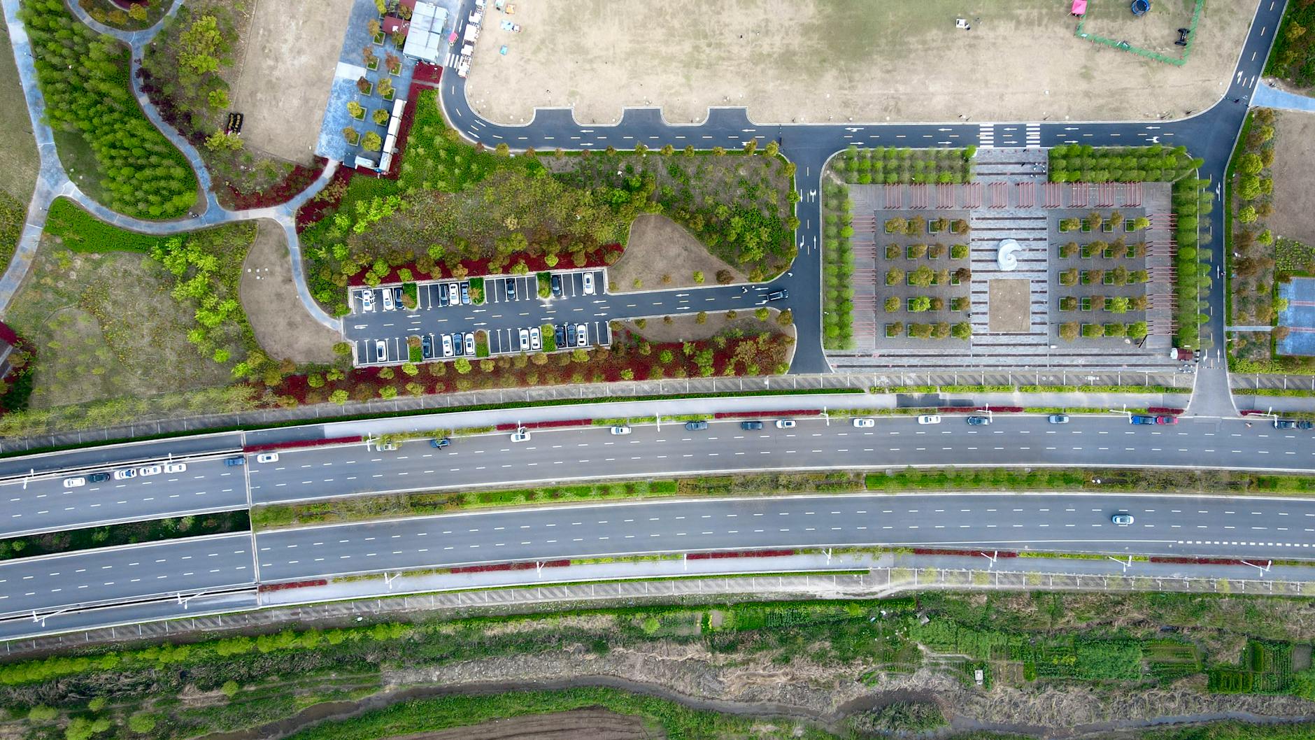 Aerial view capturing Pudong, Shanghai's highway and park landscape, featuring roads, greenery, and urban design.