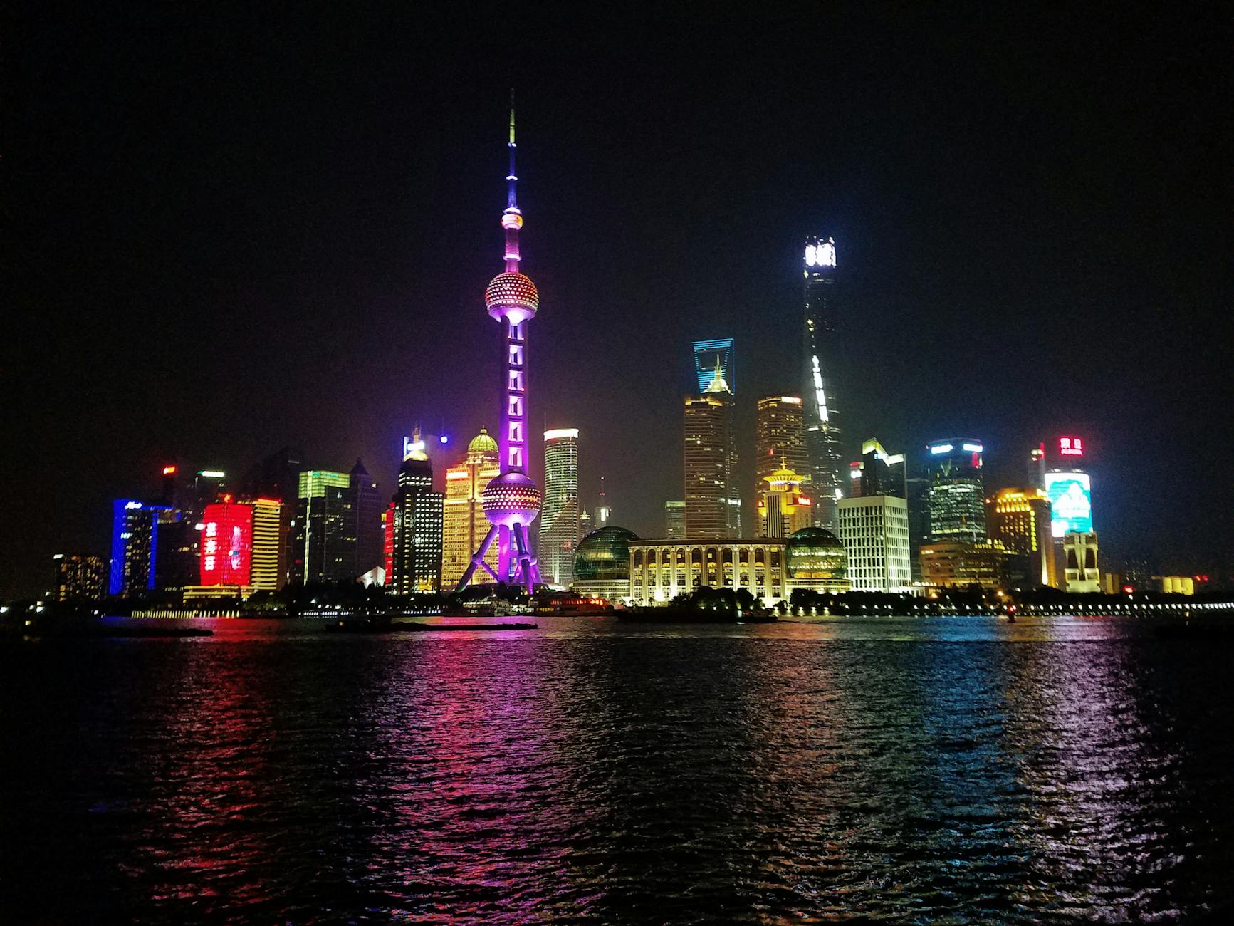 Vibrant night view of Shanghai's illuminated skyline featuring the iconic Oriental Pearl Tower.