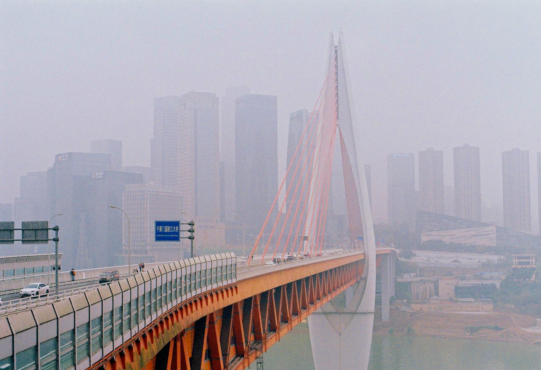 Chongqing cityscape featuring a bridge and skyscrapers enveloped in fog.