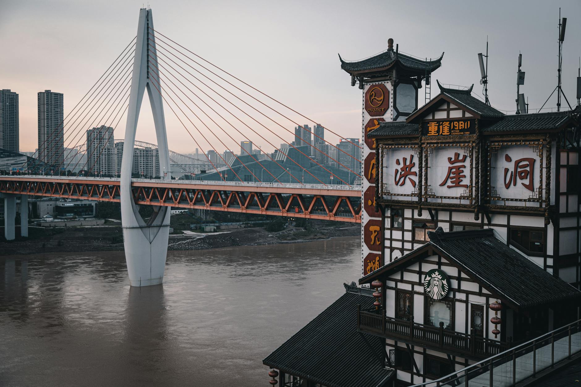 Urban cityscape of Chongqing showcasing Qiansimen Bridge and traditional architecture at dusk.