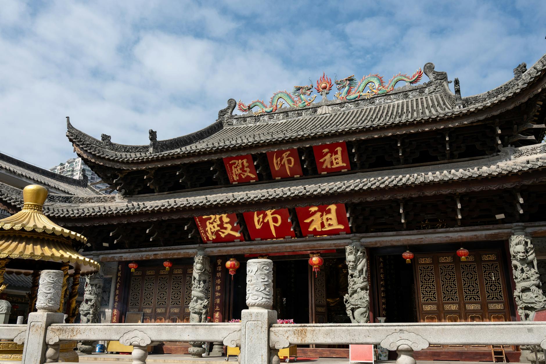 A beautiful traditional Chinese temple with intricate wooden carvings under a clear blue sky in Guangzhou, China.