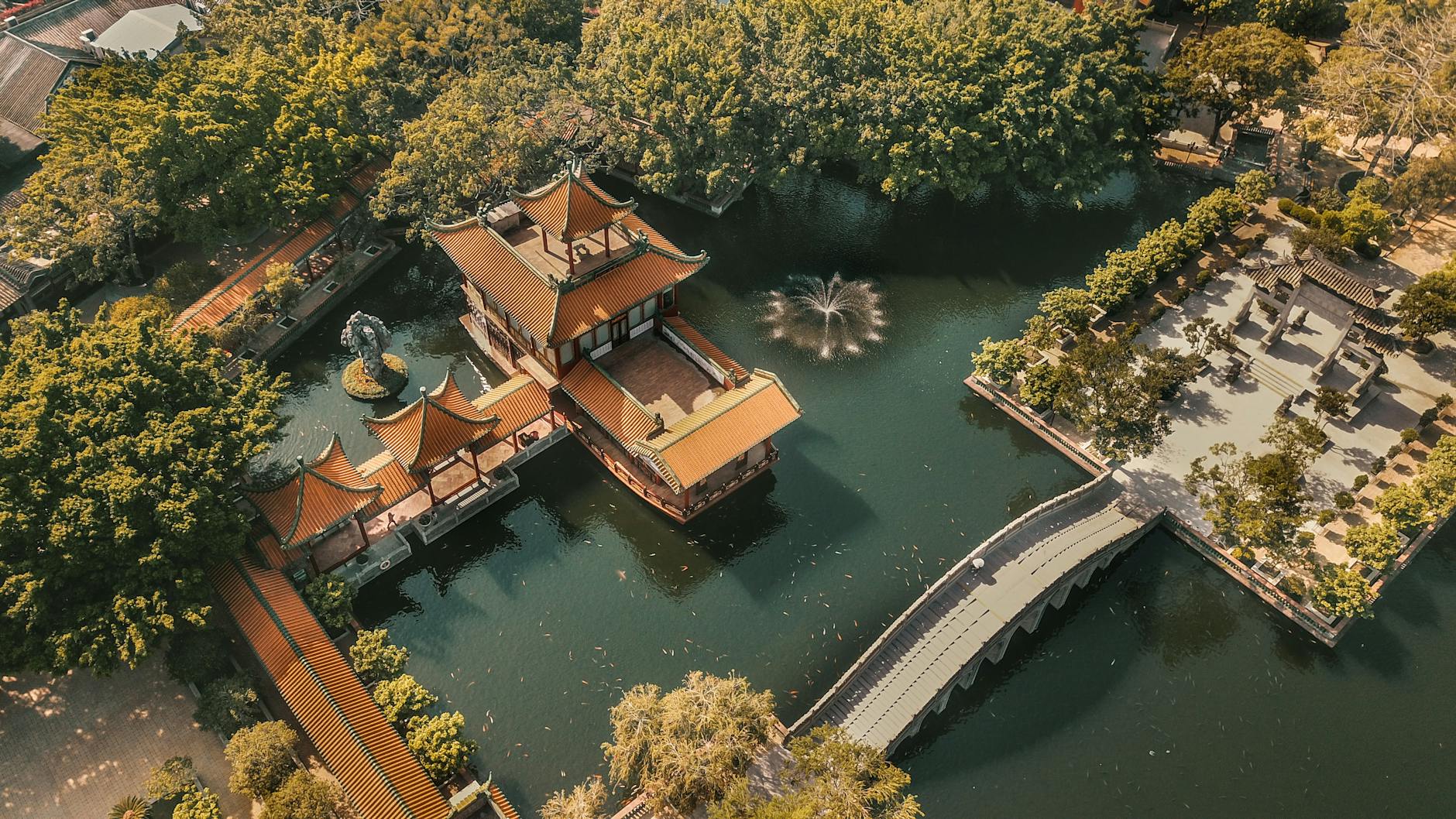 A serene aerial view of a traditional Chinese pagoda surrounded by lush greenery and water in Guangzhou Park.