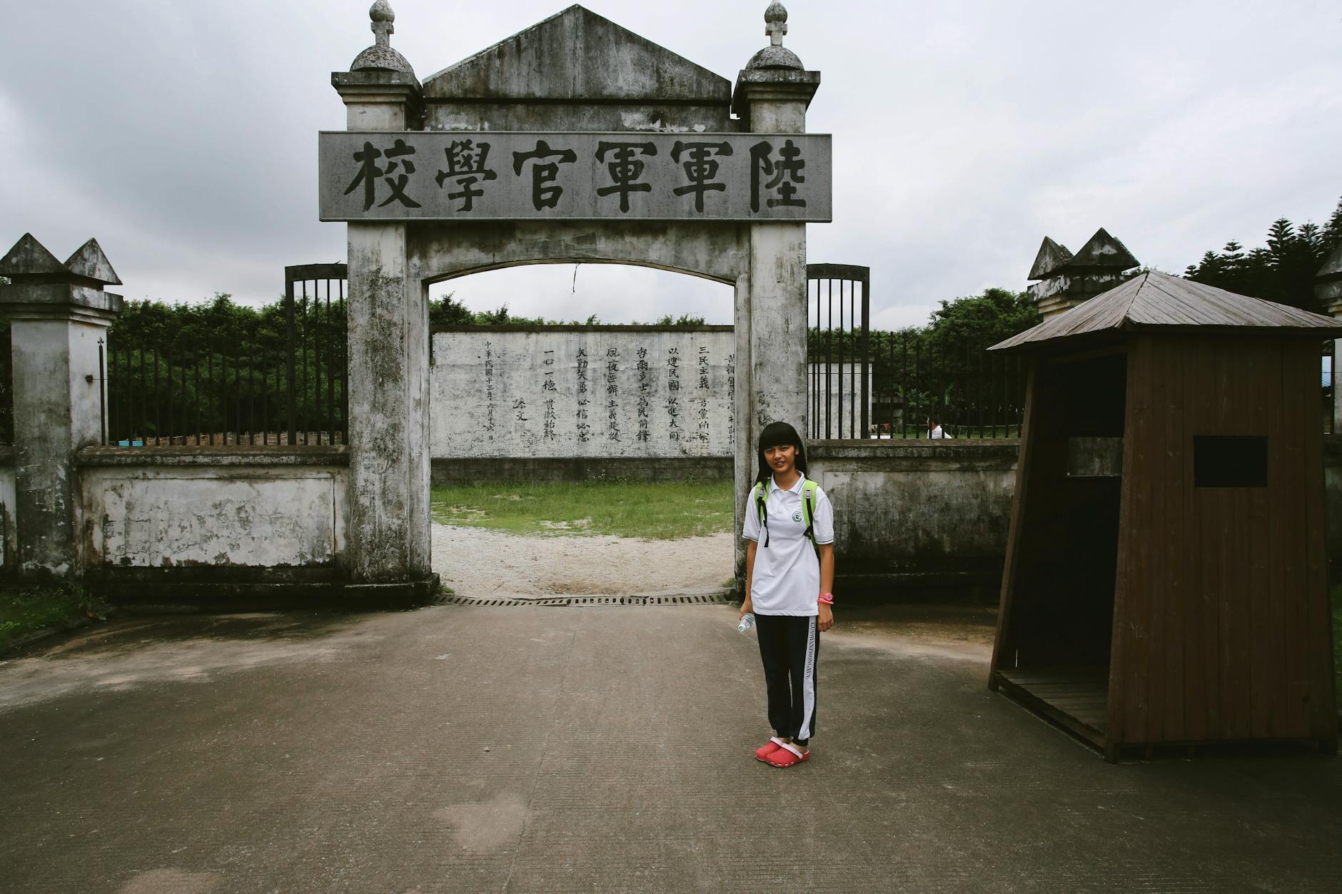 Young girl standing at Taiwan Military Academy entrance, Kaohsiung.
