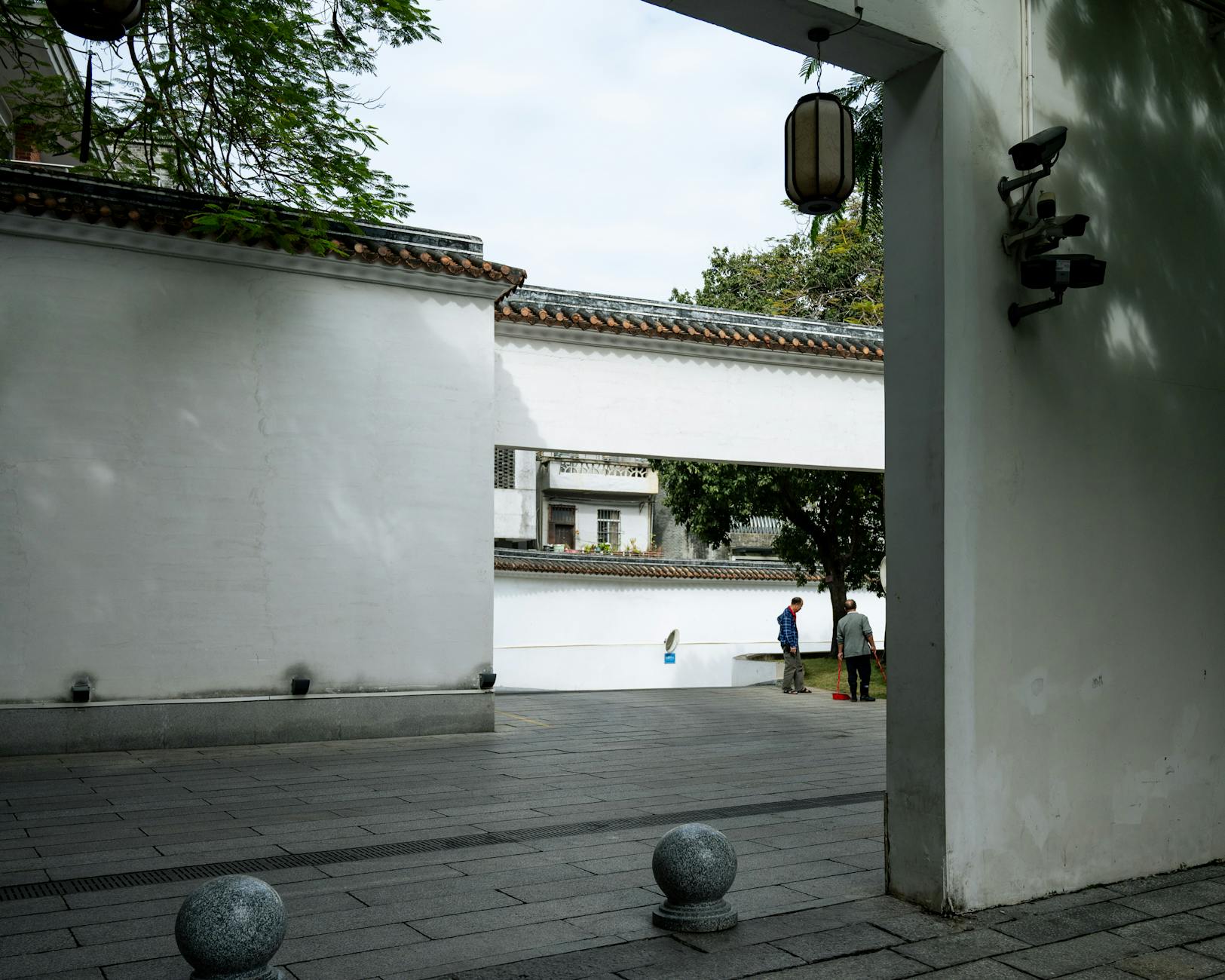Tranquil scene of traditional Cantonese courtyard in Guangzhou, China with white walls and tiled roof.