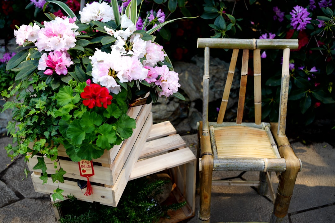 A wooden chair sitting next to a planter filled with flowers
