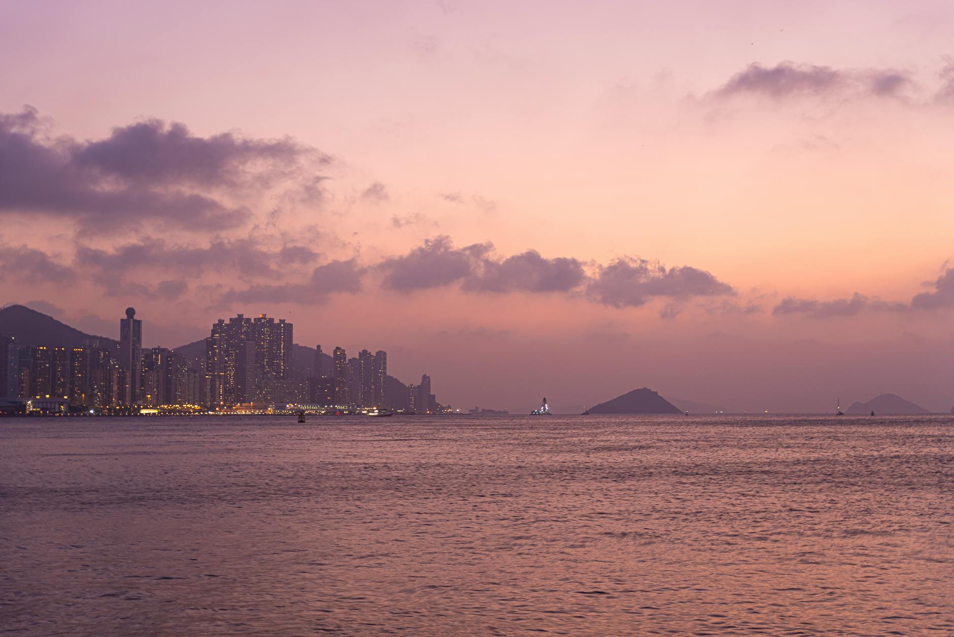 Breathtaking view of Hong Kong skyline and sea at twilight with illuminated buildings.