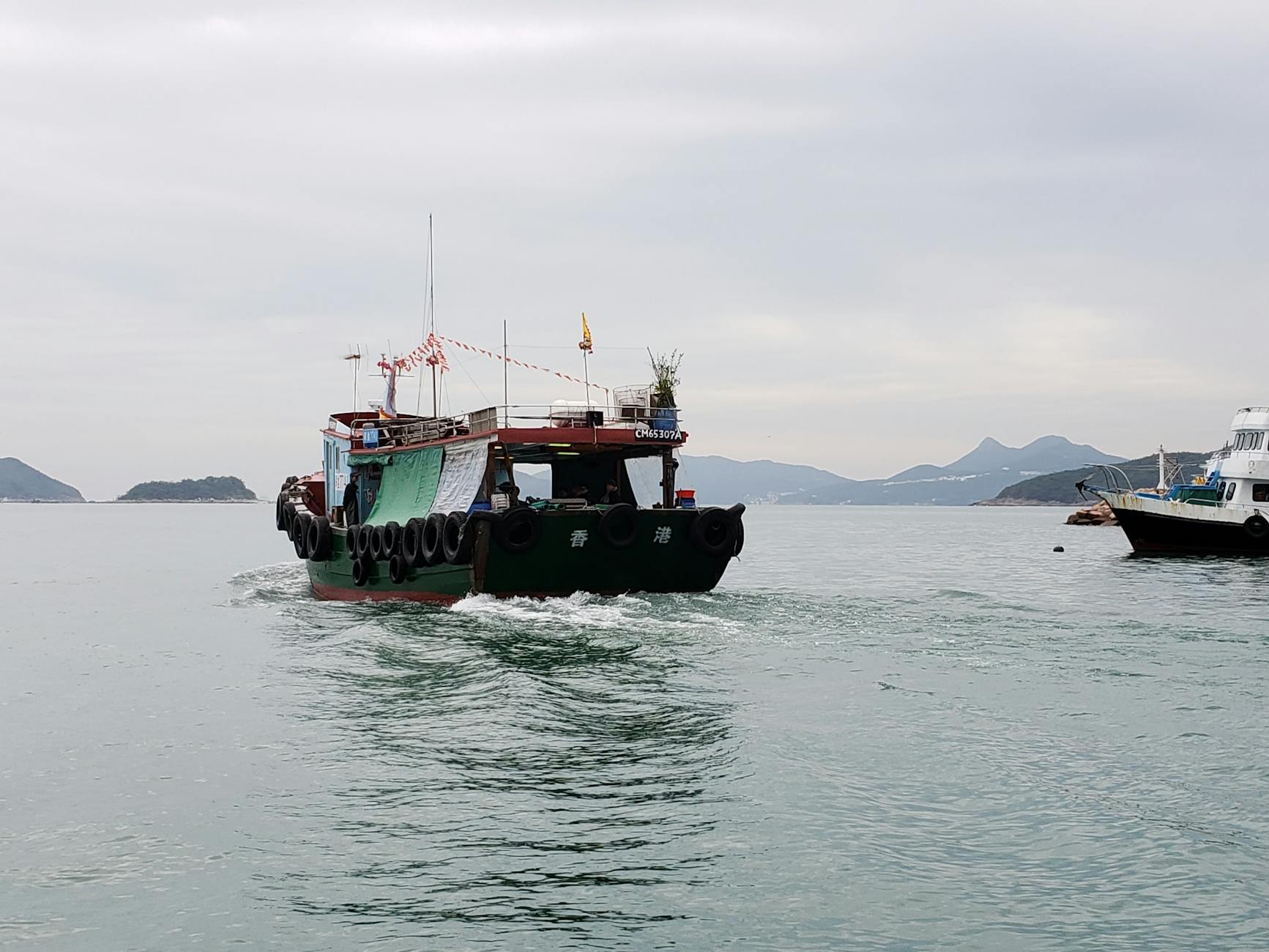 A traditional wooden fishing boat navigating the serene waters off Hong Kong.