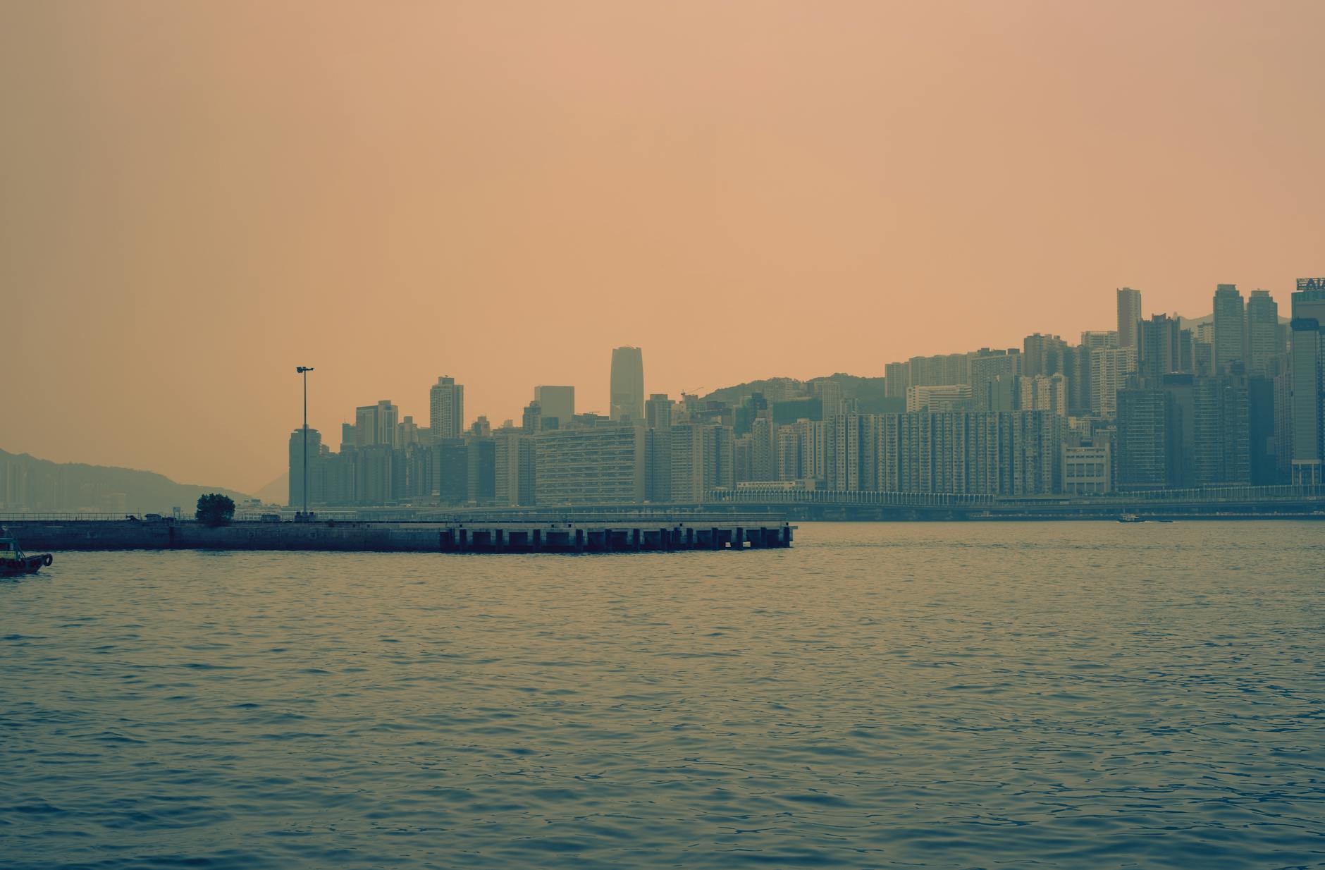Kowloon skyline at dusk, overlooking Victoria Harbour with a muted urban vibe.