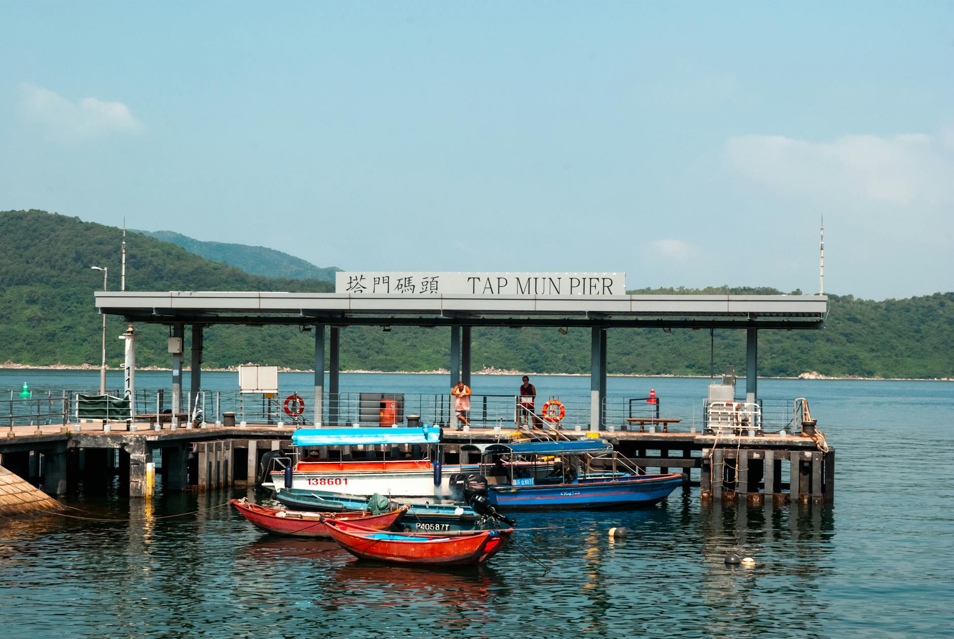 Vibrant scene of Tap Mun Pier with colorful boats under a clear blue sky.
