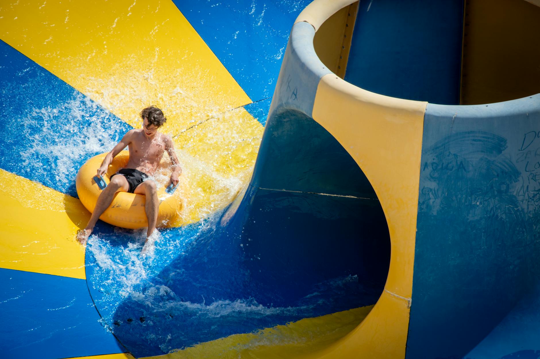 Teen enjoying a thrilling ride on a colorful waterslide at a water park.