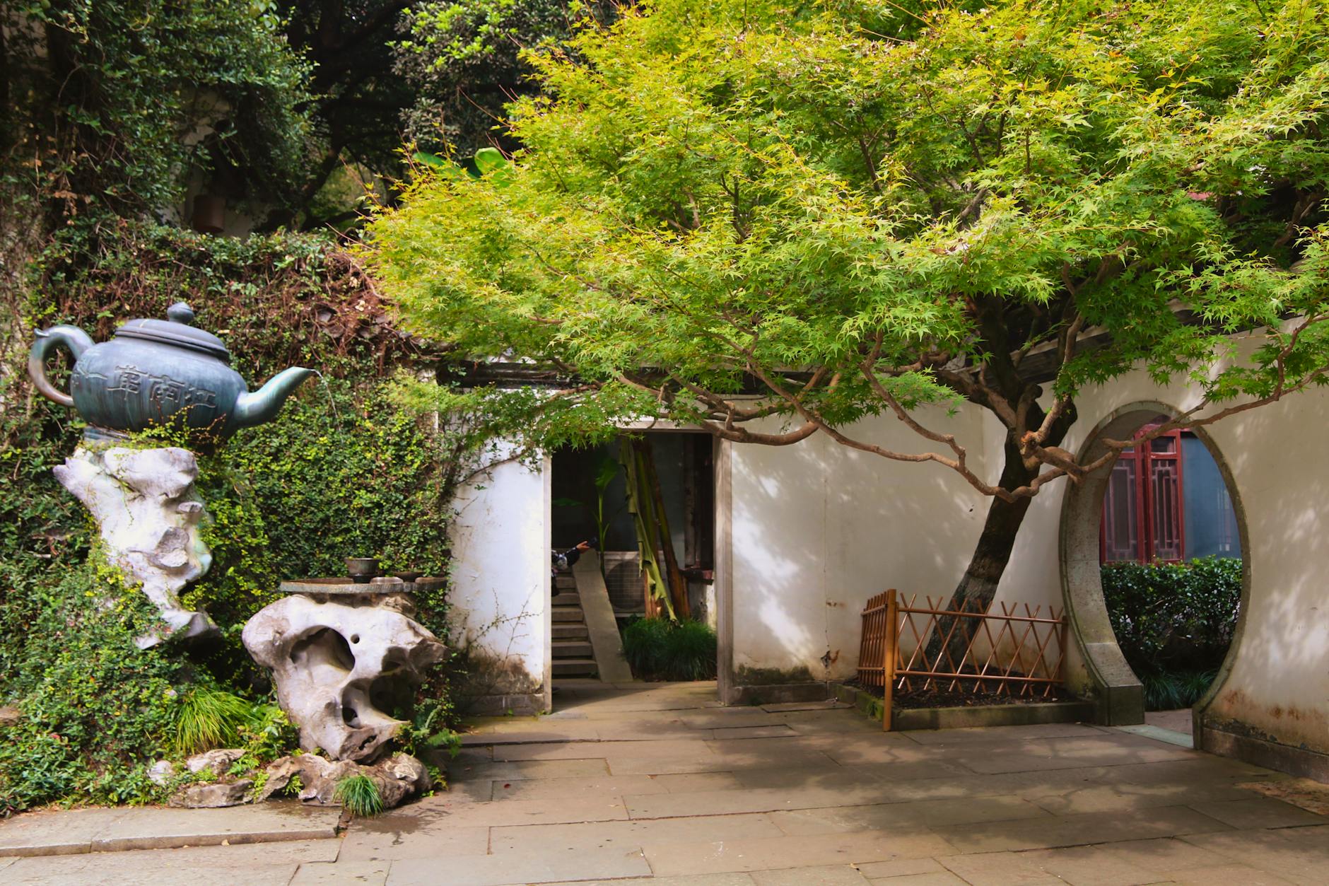 A serene scene at Hupao Park, Hangzhou, featuring lush greenery and traditional Chinese architecture.