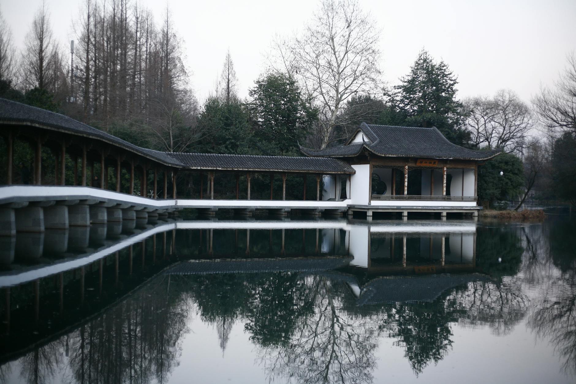Serene view of a traditional Chinese pavilion reflecting on a tranquil lake in Hangzhou, China.