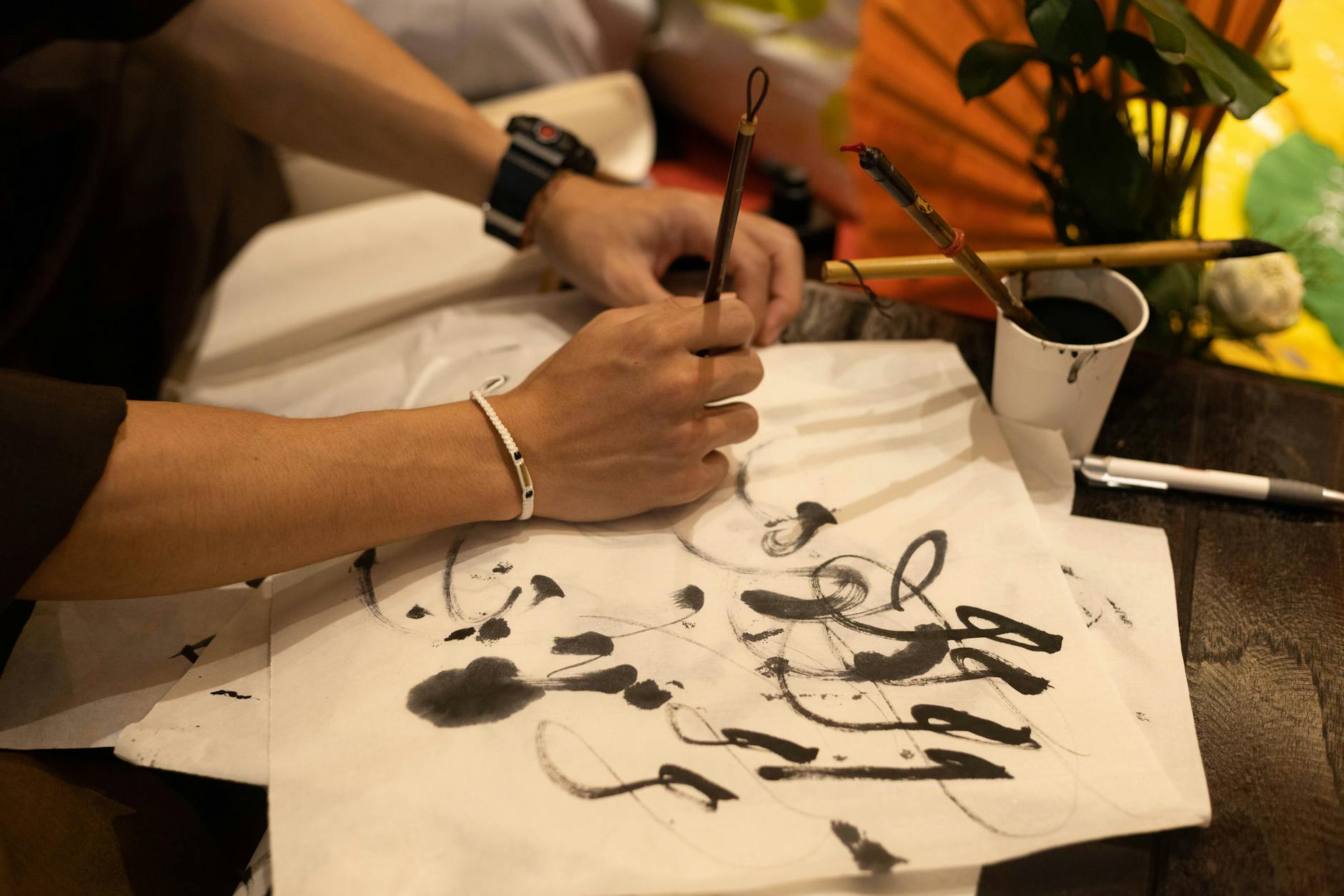 A person practicing traditional calligraphy using brushes and ink on paper.