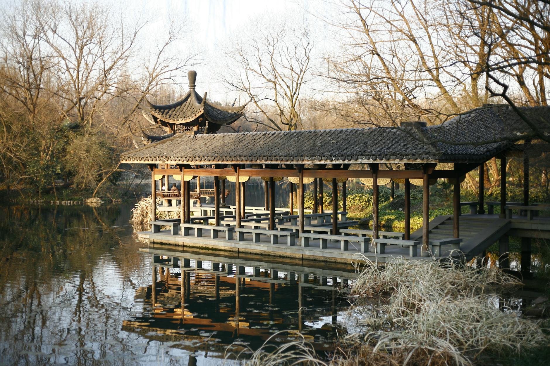 Scenic view of a traditional Chinese pavilion on a tranquil lake in Hangzhou park.