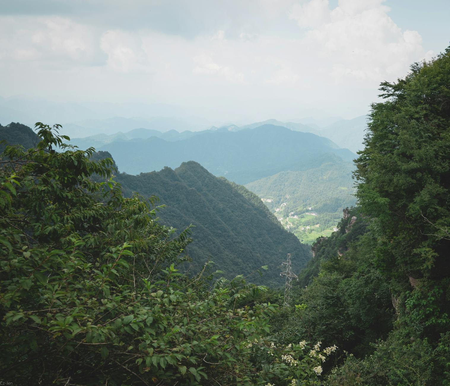 Experience the breathtaking Zhangjiajie mountainscape with lush greenery and cloudy skies.