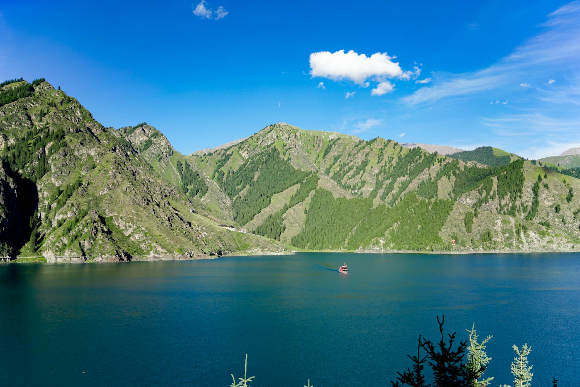 Breathtaking view of lush green mountains surrounding a tranquil blue lake under a clear sky.