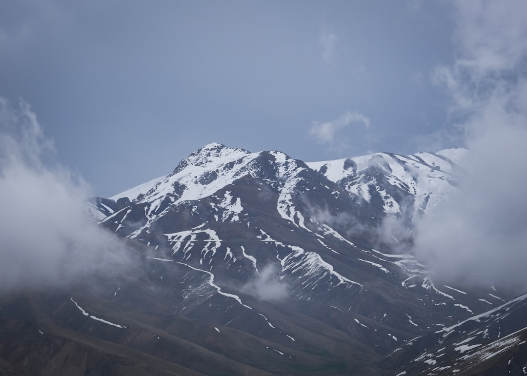 a mountain covered in snow under a cloudy sky