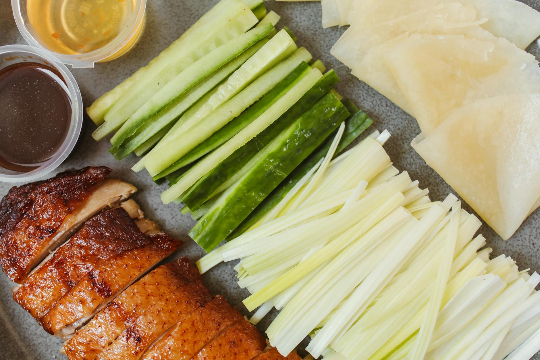 Top view of Peking duck with cucumber, onion, and sauces, ready to serve.