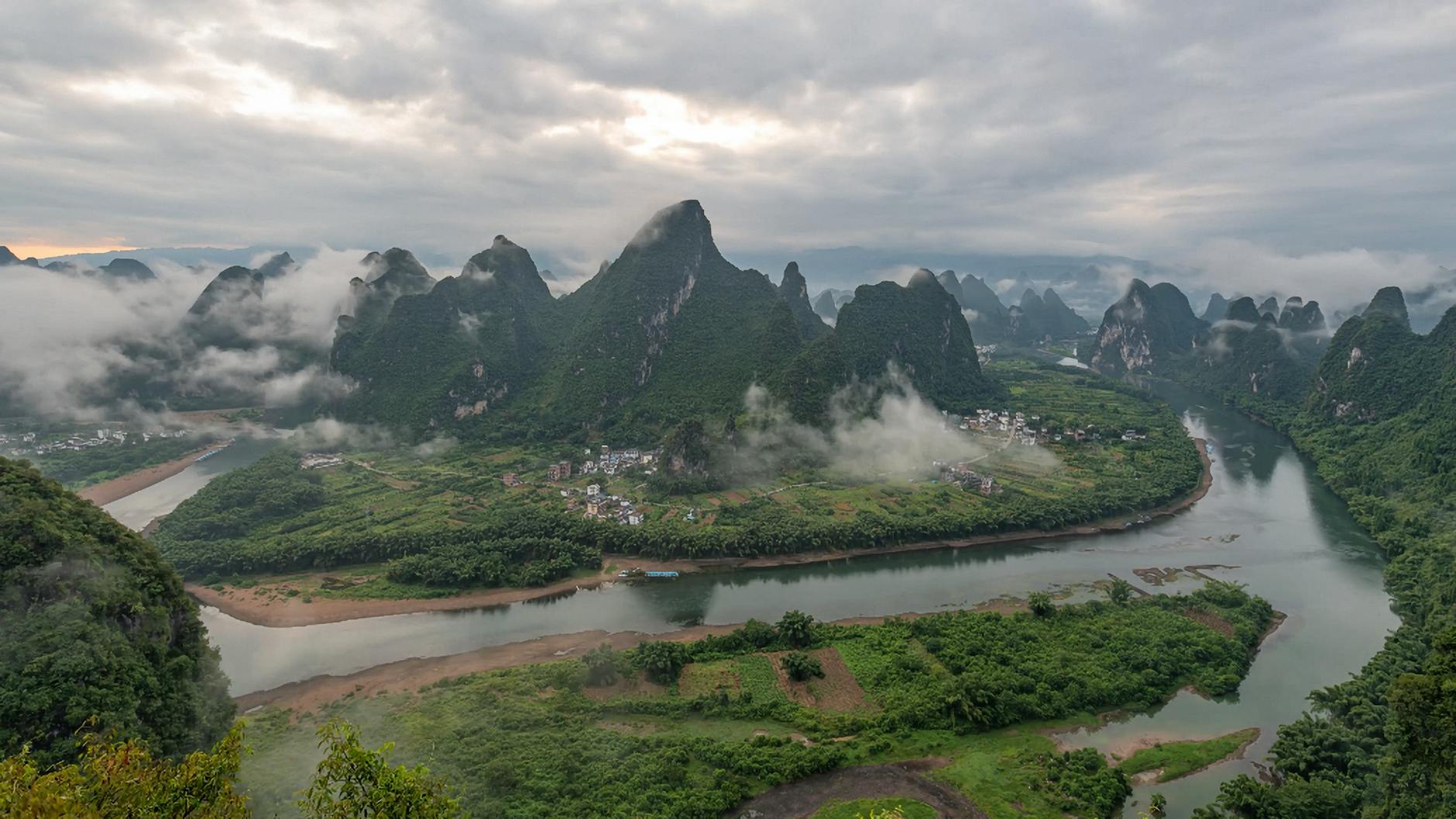 A captivating view of karst mountains and a winding river under a cloudy sky.