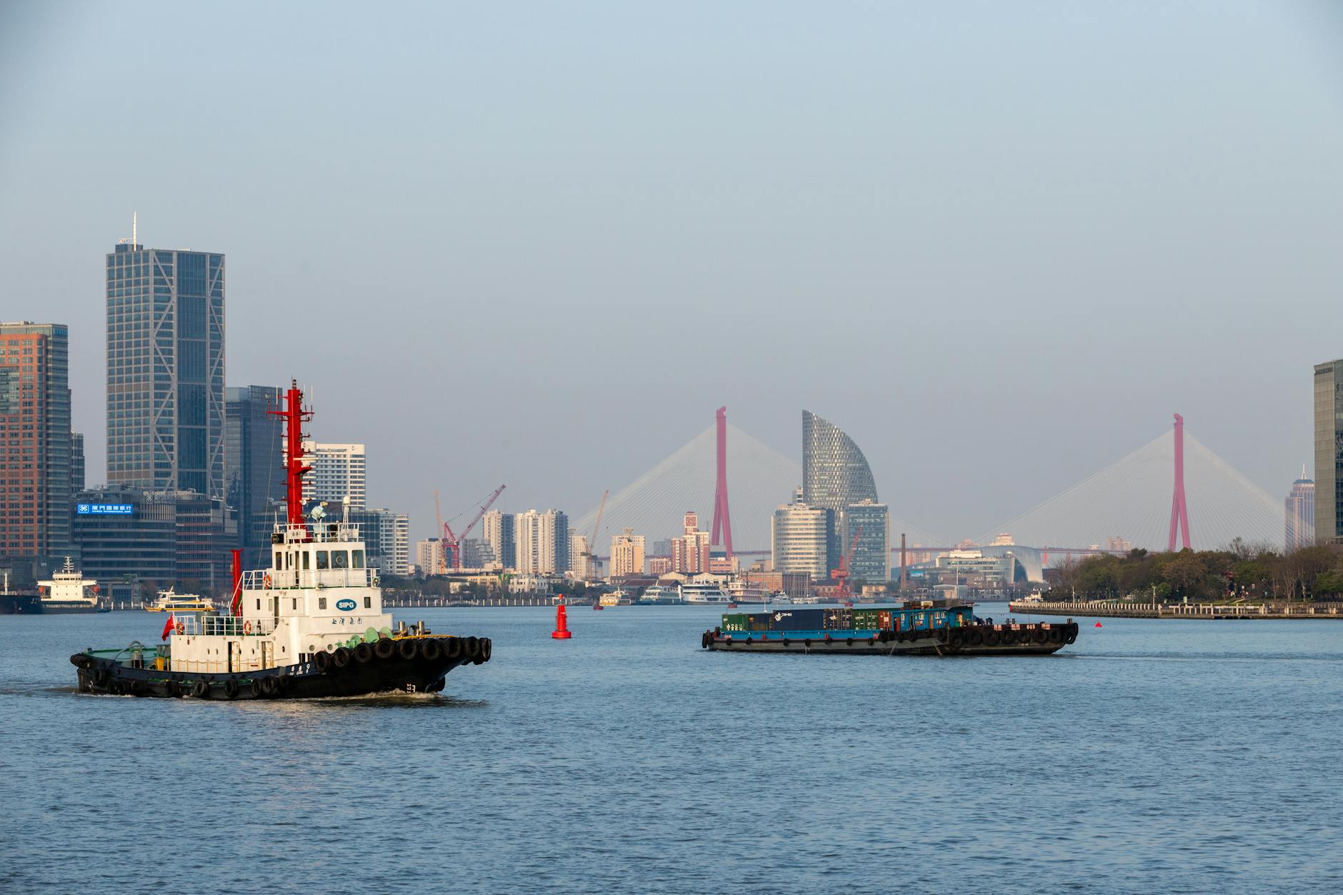 Urban skyline with tugboat and cargo barge on Huangpu River, Shanghai.