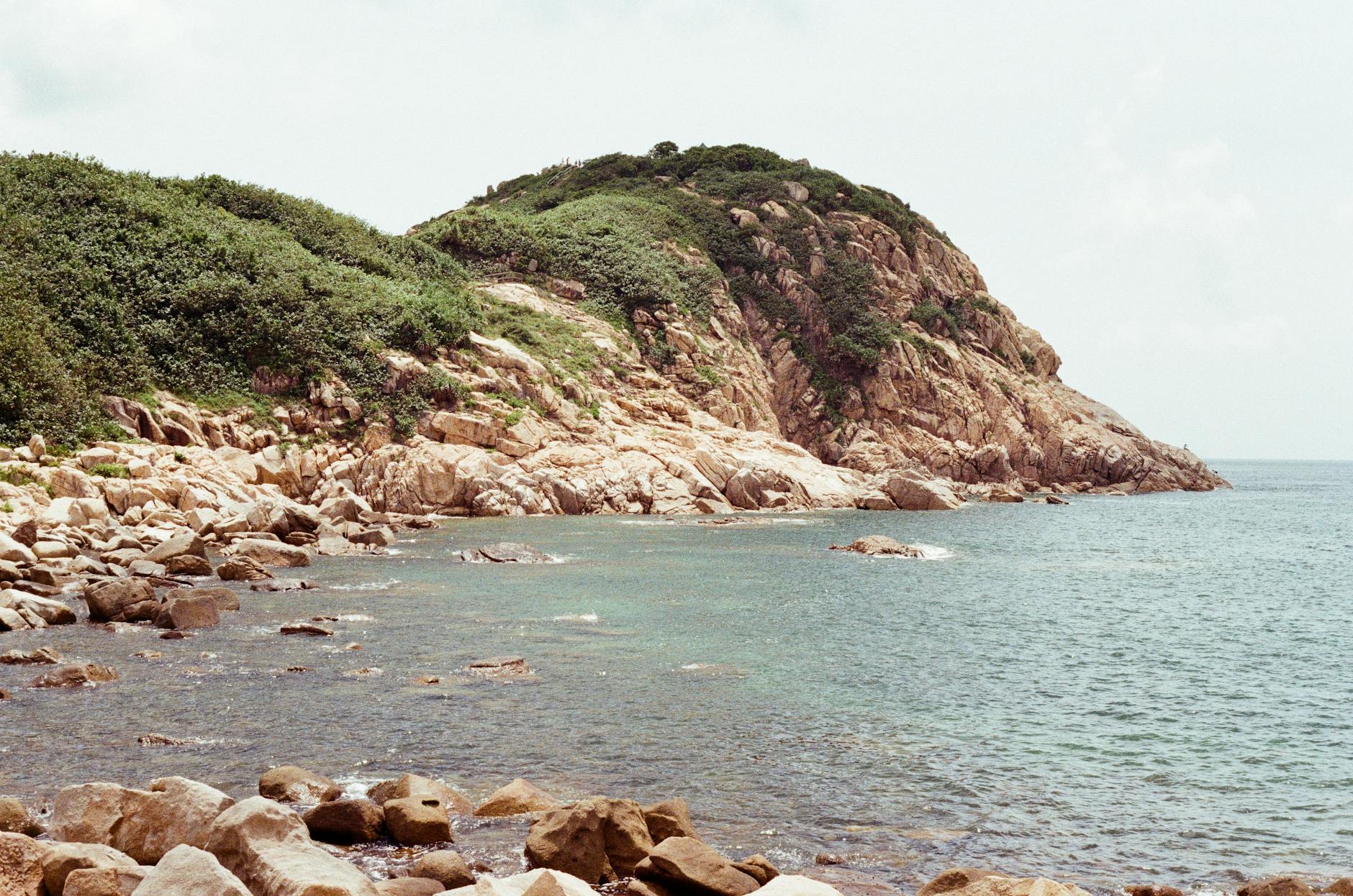 Scenic view of the rocky shoreline and lush greenery on Hong Kong Island coast.