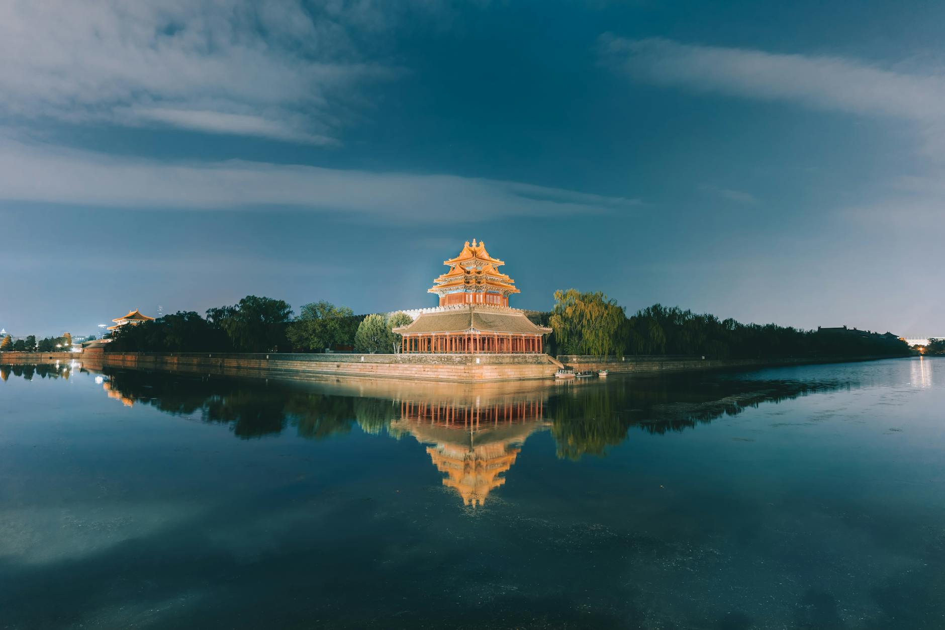 Tranquil night scene of the Northwest Tower at Beijing's Forbidden City reflecting on the water.