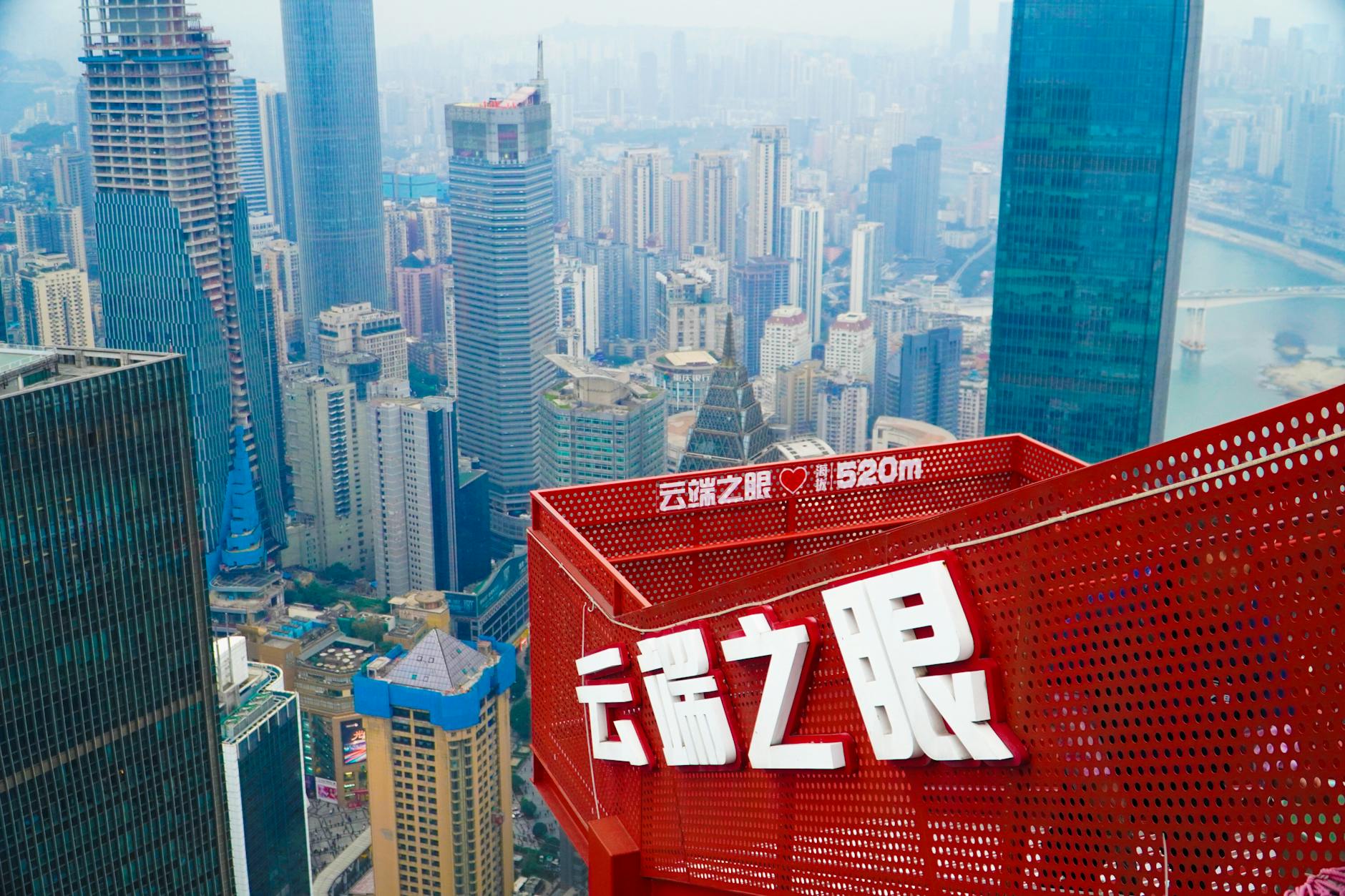Aerial view of Chongqing's urban skyline from a skyscraper rooftop, featuring modern architecture and vibrant cityscape.