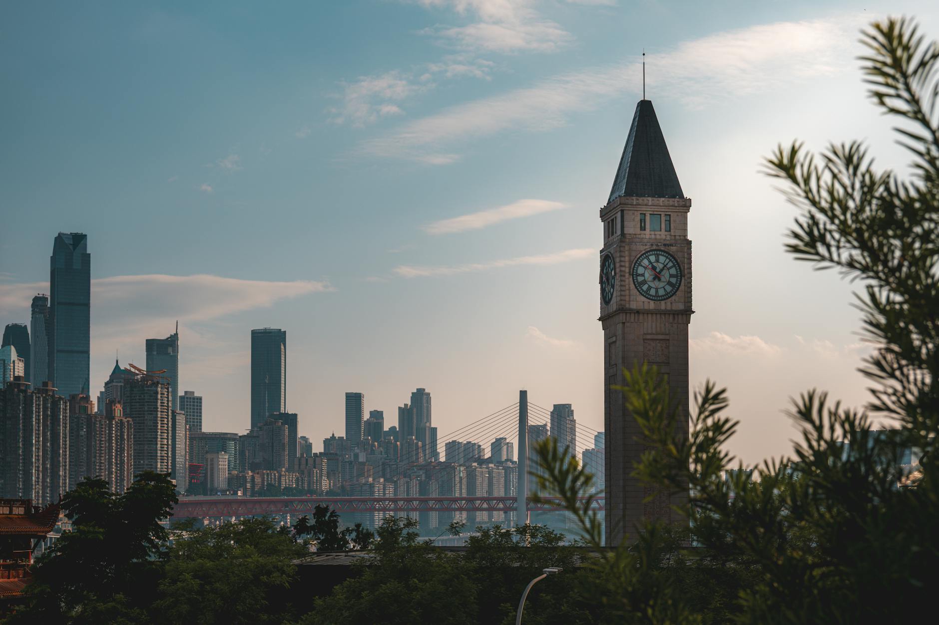 Scenic view of Chongqing skyline featuring iconic clock tower and bridge at daylight.