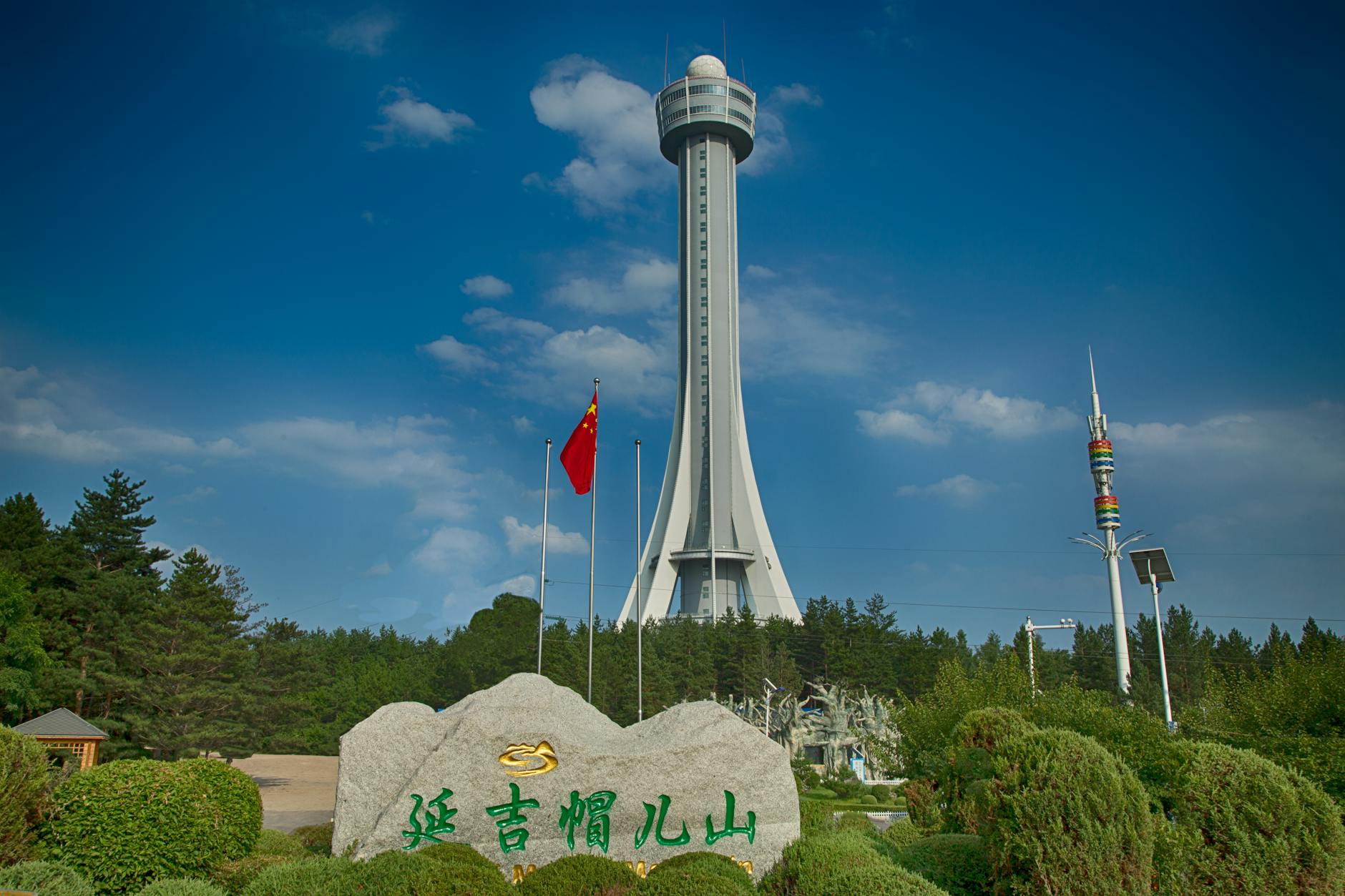 Capture of the iconic Jilin Meteorite Tower amidst lush greenery and clear skies.