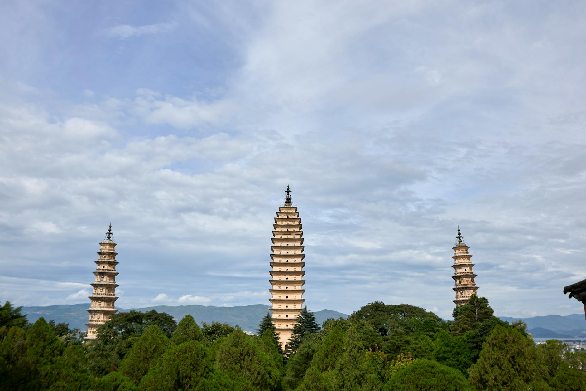 A tranquil view of three ancient pagodas surrounded by lush greenery under a blue sky.