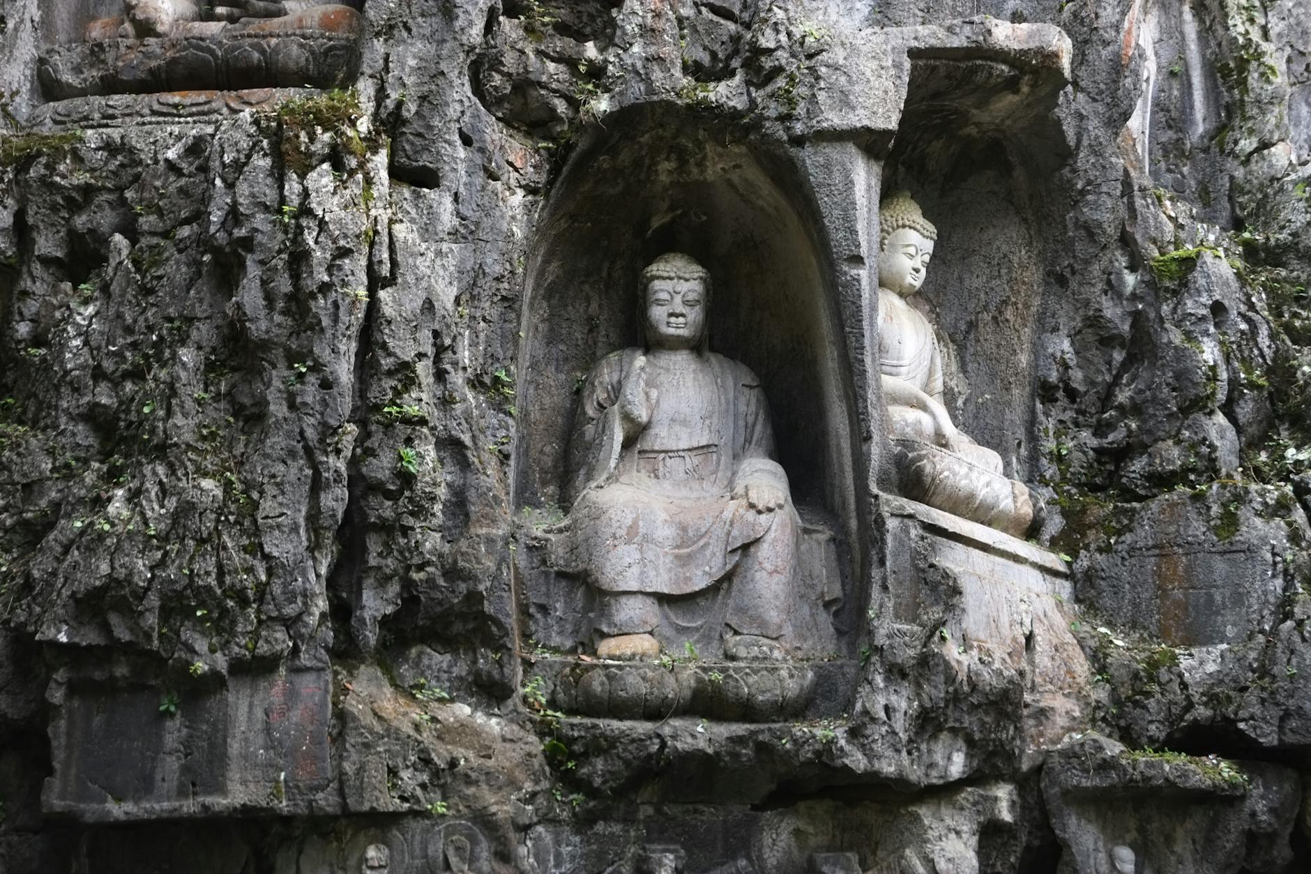 Eroded stone Buddha statues carved into a rock face at Lingyin Temple, Hangzhou.