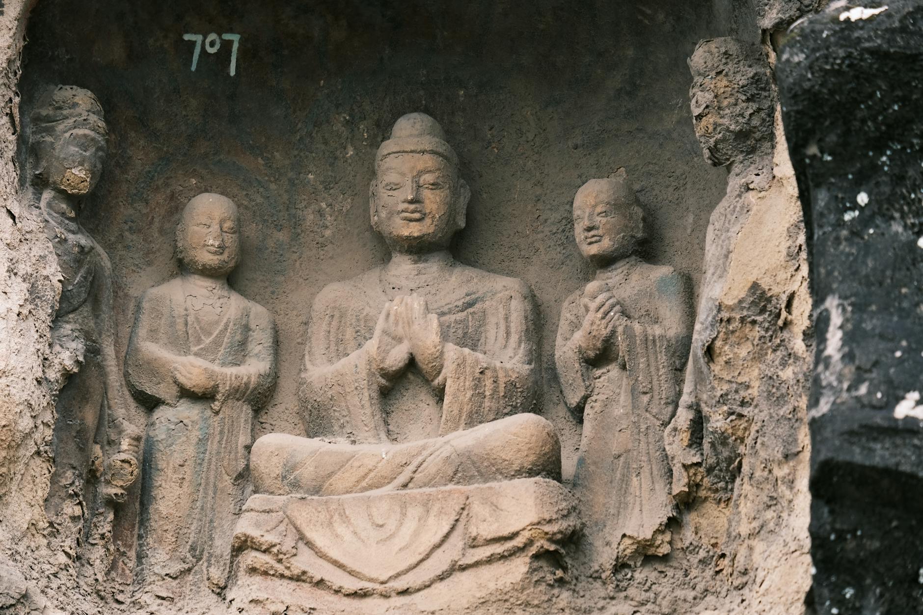 Detailed view of ancient Buddhist stone carvings inside a weathered cave.