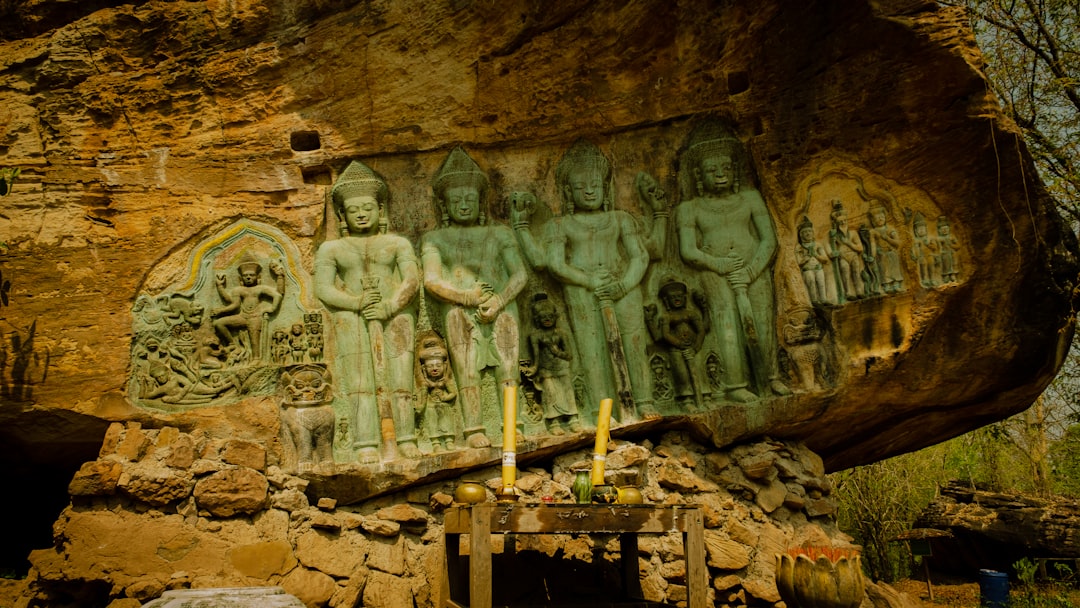 Ancient carved statues are displayed in a rocky alcove.