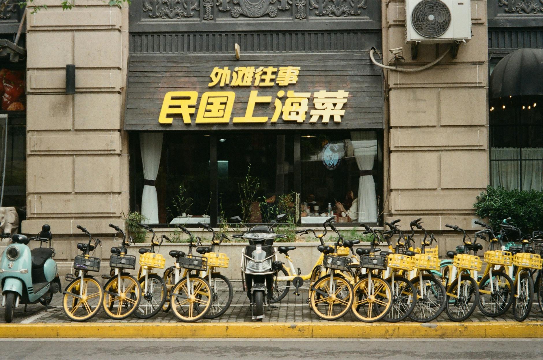 Bicycle and scooters parked outside a restaurant in vibrant Shanghai, China.